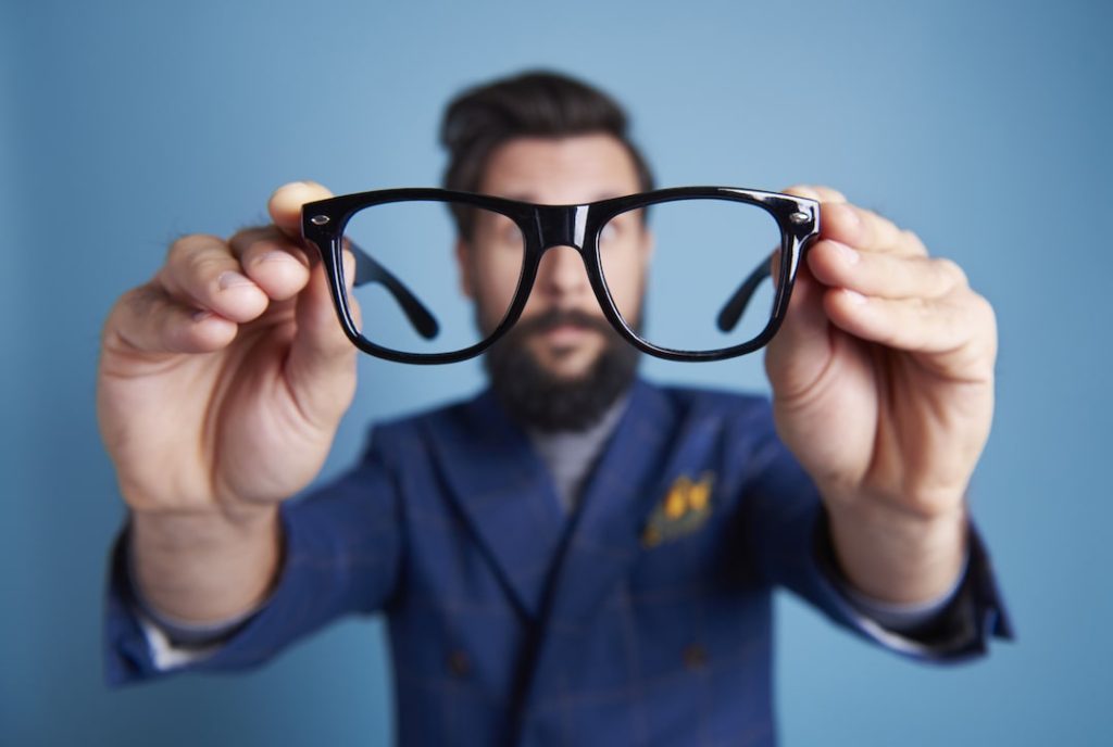 Man holding eyeglasses in front of his face